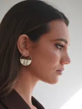 Par de aros dorados con forma circular, divididos horizontalmente: la mitad superior es un aro fino y la mitad inferior es un semicírculo sólido.