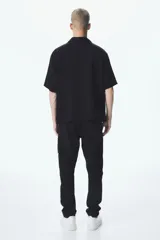 Pantalón cargo negro de corte recto, con cintura elástica ajustable con botón a presión, bolsillos laterales con cierre, bolsillos tipo parche con solapa en los laterales y bolsillos traseros insertados.