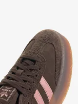 Zapatillas Adidas modelo Sambae, color marrón con detalles en rosa. Confeccionadas en cuero con refuerzos texturizados en la puntera y cordones. Suela de caucho color caramelo con dibujo multidireccional.