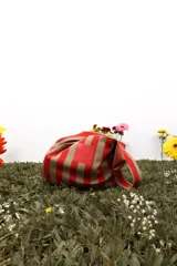 Bolso de tela a rayas verticales rojas y beige con asa superior.