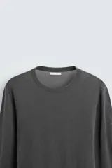 Jersey negro de lana con acabado mercerizado, corte relaxed fit, cuello redondo y mangas largas con terminaciones en rib.