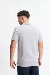 Chomba gris con textura tipo waffle, corte regular y logo bordado en el pecho.