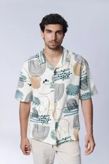 Camisa de manga corta con cuello americano y botones, con estampado abstracto en tonos beige, celeste y negro.