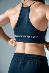 Top deportivo negro con estampado de líneas horizontales y logo de la marca en blanco.