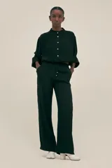 Pantalón negro de crepe con corte recto, cintura elastizada, bolsillos laterales y terminaciones en cobre.