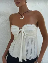 Top strapless tejido de punto color crudo, con detalle de lazo en el centro del busto.