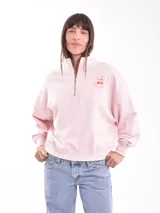 Buzo rosa de corte holgado, con cuello alto y cierre metálico parcial. Estampado pequeño de cerezas en el pecho.