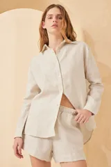 Camisa beige de lino, de corte holgado, manga larga y cuello clásico.