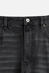 Pantalón de jean negro con efecto lavado, corte flare, cinco bolsillos, cierre frontal con cremallera y botón, y bajo con acabado irregular.