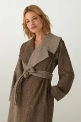 Tapado largo color beige con diseño de espiga, cuello solapa, cierre cruzado con cinturón y bolsillos laterales. Confeccionado en lana fina sin teñir.