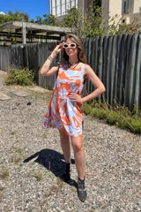 Vestido corto con estampado abstracto en tonos naranja y celeste, escote en V y sin mangas.