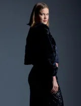 Chaqueta corta (crop) de piel sintética negra, con mangas largas abullonadas y abertura frontal.