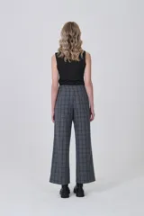 Pantalón de poliéster con estampado tartán en tonos grises y azules. Diseño de tiro medio, corte recto y ancho, con detalle de lazo ajustable en la cintura.