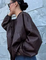 Campera bomber oversize color marrón oscuro con cierre frontal y bolsillos laterales. Tiene elástico en la parte inferior y en los puños.