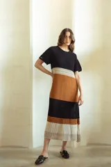 Vestido largo tejido a crochet con diseño a rayas horizontales en colores negro, marrón, beige y blanco.