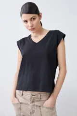 Remera verde pistacho de corte recto, con cuello en V y botones decorativos en los hombros.