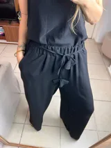 Mono negro de breteles finos con cintura elastizada y lazo ajustable. Pantalón palazzo de corte amplio.