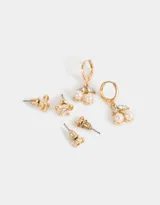 Set de tres pares de aros dorados: un par de aros tipo botón, un par de aros con forma de moño y un par de aros colgantes con forma de cerezas con perlas.