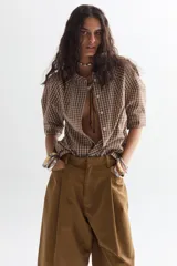 Camisa a cuadros color marrón y blanco, de corte recto, con cuello mao y mangas 3/4 abullonadas. Se abrocha con botones y tiene lazo ajustable en el escote.