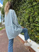 Camisa oversize celeste con rayas verticales blancas, de manga larga y cuello clásico.