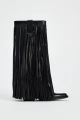 Bota de cuero negra con estilo cowboy, caña media y punta fina. Presenta detalle de flecos largos en el cuerpo y tiradores laterales.