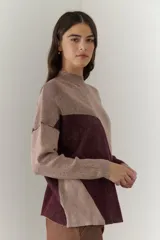 Buzo de punto con diseño geométrico en bloques de color gris y negro, de cuello redondo y mangas largas.