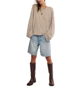 Buzo de punto waffle color beige, de algodón suave, con silueta relajada, hombros caídos, mangas largas, bolsillo frontal y escote amplio tipo barco.