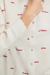 Pijama camisero crudo de algodón y lino, con bordados de palabras en rojo y ondas en los ruedos. El pantalón tiene bolsillos laterales.