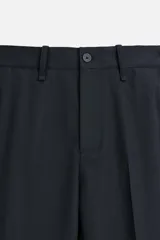 Pantalón de vestir azul marino, de corte recto, con bolsillos laterales y traseros. Incluye un bolsillo tipo cargo en la pierna izquierda. Se ajusta a la cintura con cinturón de cuero marrón.