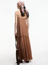 Vestido largo color marrón, con escote en V y breteles finos regulables. La falda tiene un corte con vuelo y una sección inferior de tela transparente.