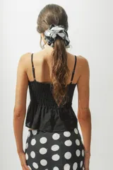 Top blanco con breteles finos y detalle de nudo en el centro del busto.