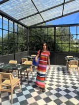 Vestido largo tejido con hilo de algodón a rayas horizontales en tonos marrón, beige, blanco y negro. Tiene cuello redondo y mangas cortas. Tejido a mano con terminaciones en crochet.