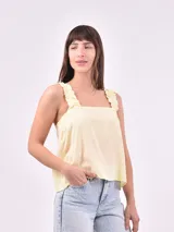 Blusa sin mangas color amarillo pálido, con breteles anchos con volados y escote cuadrado.