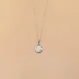 Conjunto de plata con dije circular de nácar y circonias, con dije de luna y estrella.