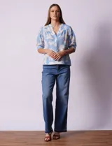 Blusa de gasa estampada con flores blancas sobre fondo celeste, marca Floral & Ivy. Cuello a la base con escote en V. Manga corta con detalle de puño y botón.