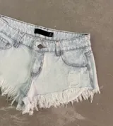 Short de jean celeste con efecto lavado, tiro alto, bolsillos delanteros y traseros, y terminación desflecada.