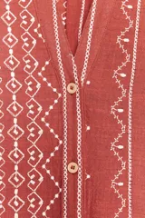 Camisa color ladrillo con bordados blancos, de cuello redondo y escote pico, manga 3/4 y cierre frontal con botones.