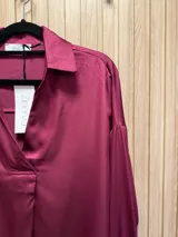 Blusa de seda color fucsia, de corte holgado y mangas largas con puños abotonados.