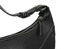 Cartera negra de cuero sintético con forma de media luna y costuras blancas.
