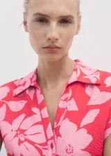 Vestido midi de manga corta con cuello camisero y cierre de botones frontal. Presenta un estampado floral en tonos rosados y un cinturón ajustable a juego.