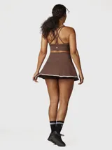 Falda deportiva tipo skort color chocolate con borde inferior en contraste blanco. Confeccionada en tejido técnico con short integrado y bolsillo oculto.