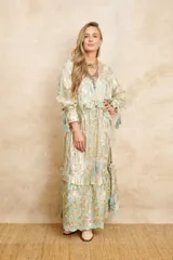Vestido largo estilo hindú con estampado floral en tonos dorados y celestes, con bordados dorados, escote en V y mangas largas con volados y borlas decorativas.