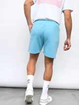 Bermuda gris de felpa sin friza, con cintura elástica ajustable con cordón y logo Umbro estampado en rojo en la pierna izquierda.