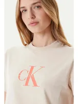 Remera color crema de algodón, con cuello redondo y logo de Calvin Klein estampado en color coral en el pecho.