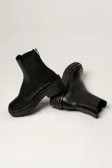 Botas Chelsea negras de cuero, con plataforma track y detalle de tachas plateadas en la suela.