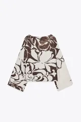 Blusa de cuello redondo y manga larga ancha con botones en los hombros. Estampado floral en tonos marrón y blanco.