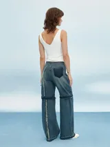Pantalón de jean azul de corte ancho con aberturas a la altura de las rodillas.