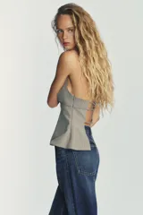 Top color gris con raya diplomática, de cuello halter ajustable y escote redondo. Espalda descubierta con tiras ajustables, forro interior y cierre lateral con cremallera oculta.