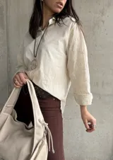 Camisa beige de manga larga con bordado floral en las mangas y cuello clásico.