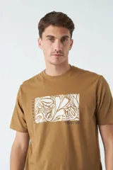 Remera color ocre de corte recto y manga corta, con cuello redondo y estampado rectangular con diseño floral en el frente.